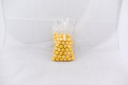 Clear plastic bag filled with shiny yellow gumballs against a white background.