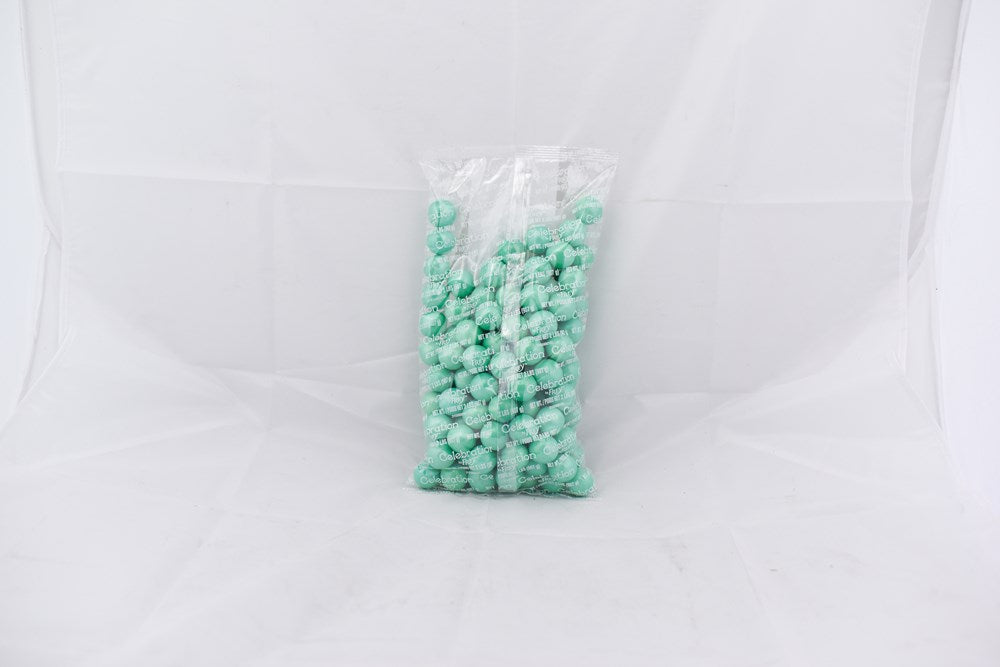 Clear plastic bag filled with shiny turquoise spherical gumballs against a white background.