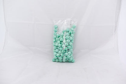 Clear plastic bag filled with shiny turquoise spherical gumballs against a white background.