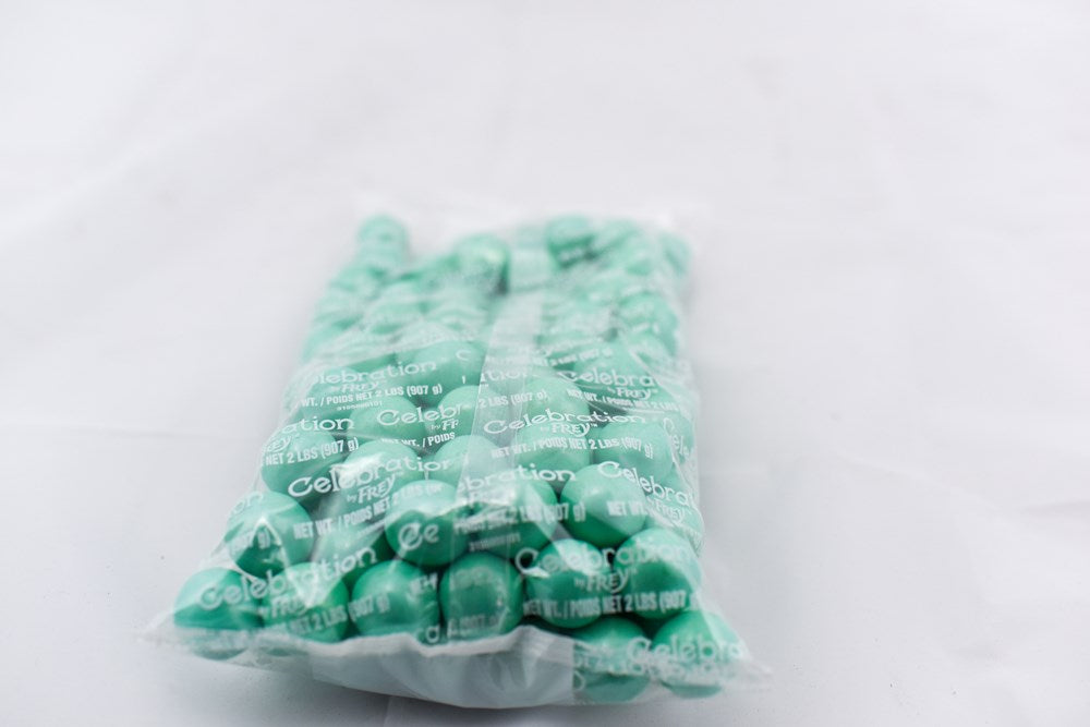 Clear plastic bag filled with shiny turquoise gumballs, each perfectly round and glossy.