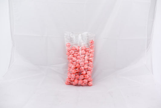 Clear plastic bag filled with shiny pastel coral-colored round gumballs.