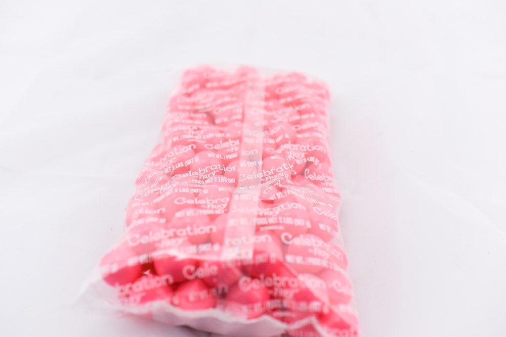 Clear plastic bag filled with bright pink round gumballs, tightly packed and sealed.