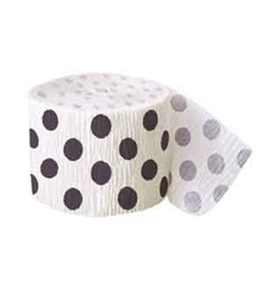 White crepe paper streamer with large black polka dots, rolled with a loose end visible.