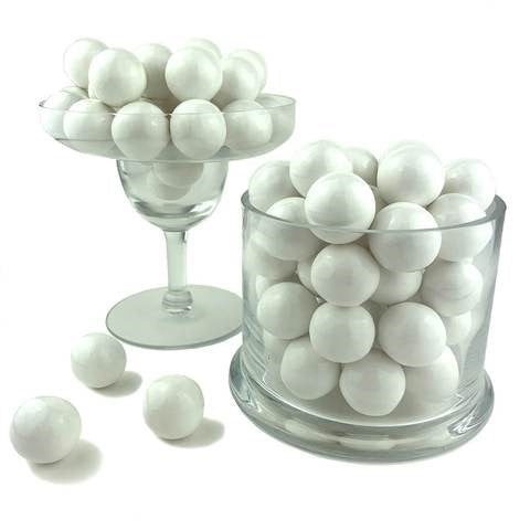 Glossy white spherical gumballs stacked in clear glass containers with a smooth, shiny surface.