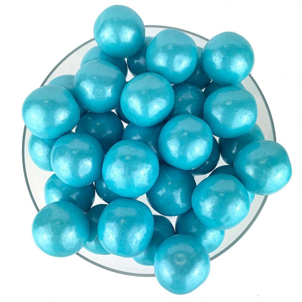 Shiny powder blue spherical gumballs with a smooth, glossy finish in a clear glass bowl.