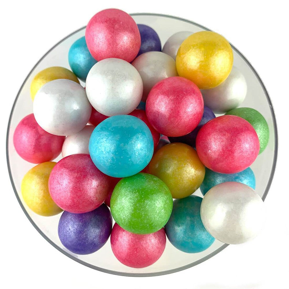 Shiny spherical gumballs in pastel colors including pink, blue, green, yellow, purple, and white arranged in a white bowl.