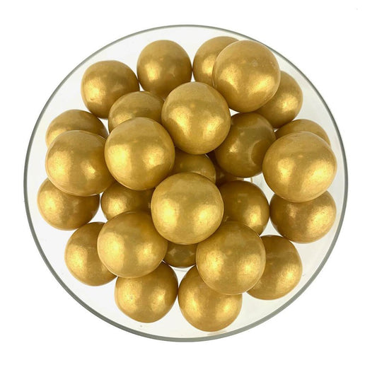 Glossy gold spherical gumballs with a smooth, shiny surface in a clear round bowl.