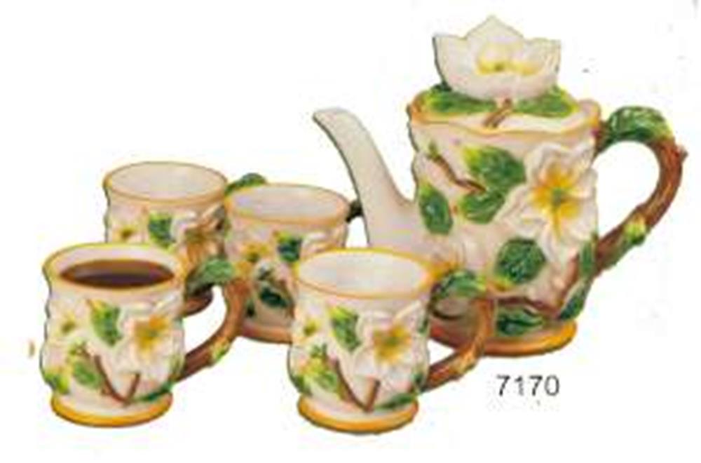 Ceramic floral tea set with white flowers and green leaves, includes teapot and four matching cups.