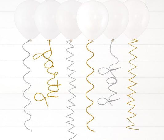 White helium balloons with silver and gold spiral pipe cleaner tails spelling out "party" and "wow" in cursive letters.