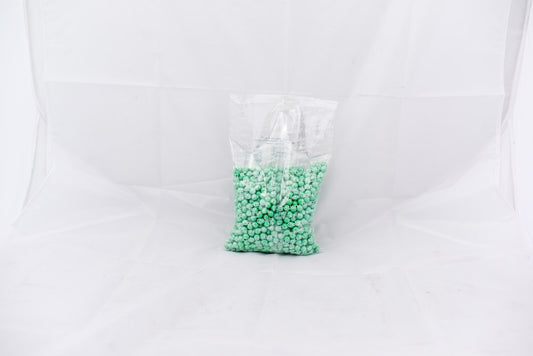 Clear plastic bag filled with small turquoise round beads labeled Shimmer SiXLets, 2-pound size.