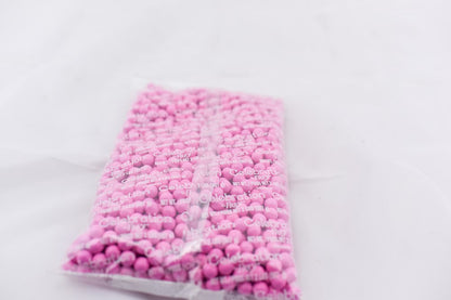 Clear plastic bag filled with small, round, light pink pellets or beads, sealed at the top.