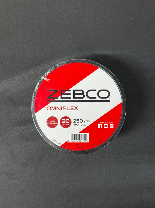 Round spool of Zebco Omniflex 30lb fishing line with red and white label on a dark surface.