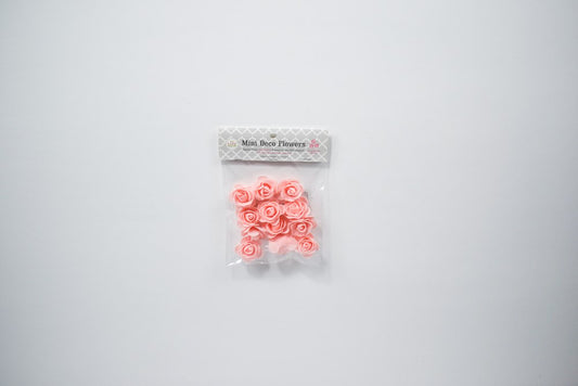 Twelve small blush pink foam flowers with delicate petal shapes in clear plastic packaging.