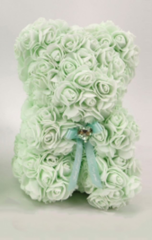 Mint green teddy bear made of foam roses with a small blue ribbon bow on its neck.