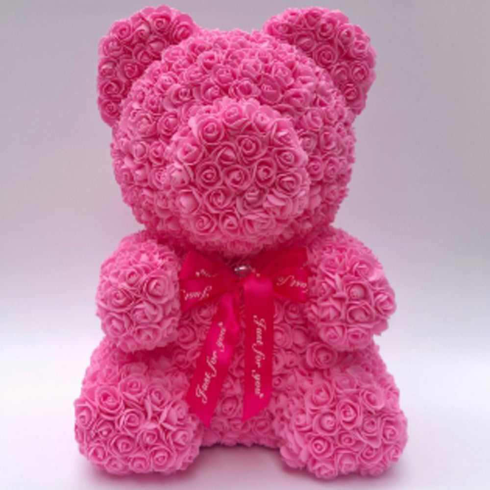Pink teddy bear made of foam roses with a red bow around its neck, 20 inches tall.