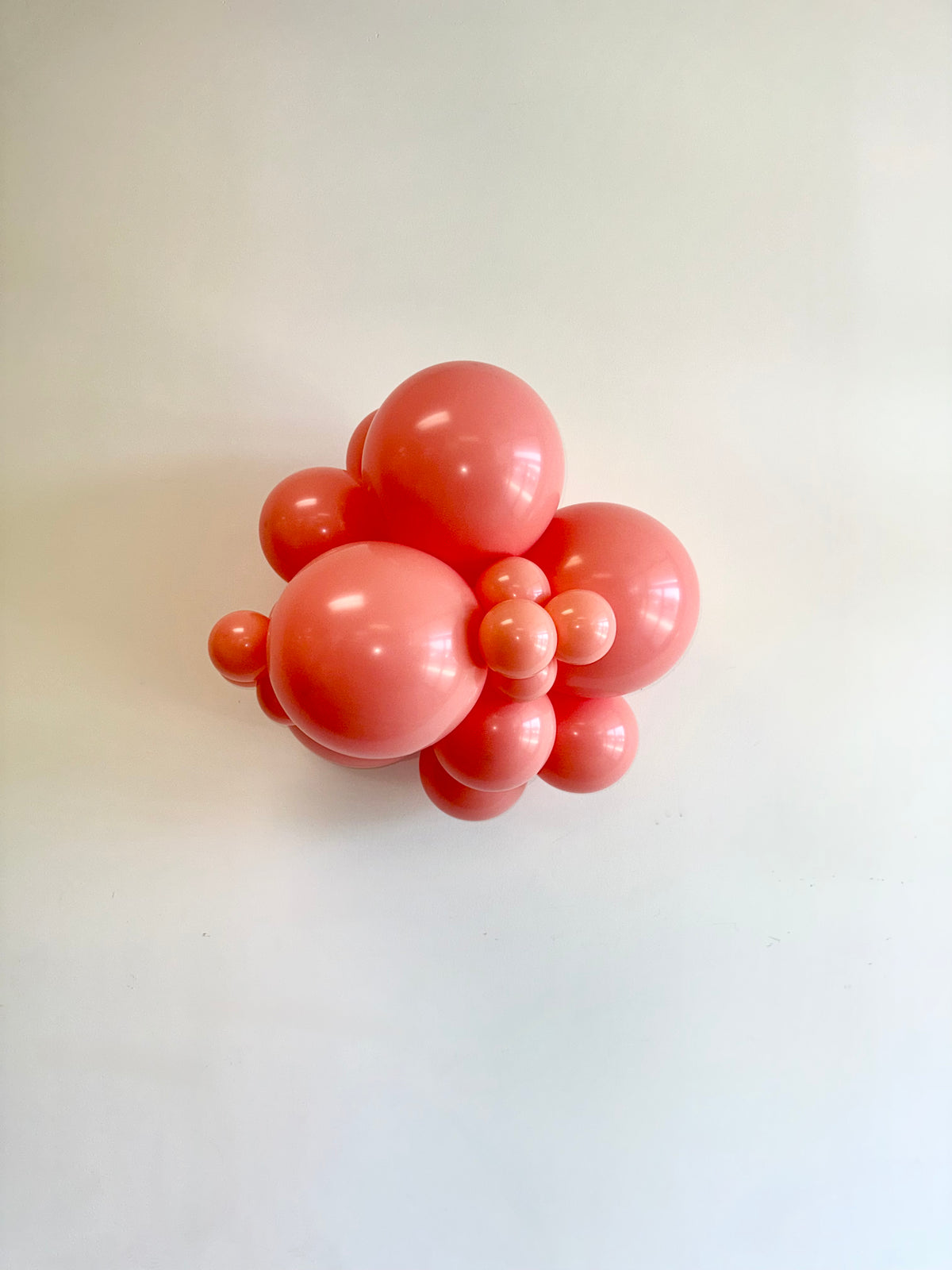 Cluster of glossy poppy red latex balloons in various sizes arranged together.