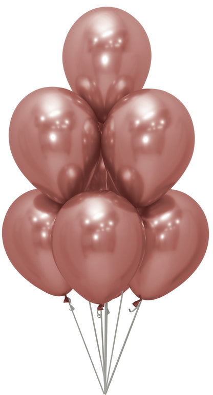 Seven shiny rose gold latex balloons inflated with helium, clustered and floating upward.