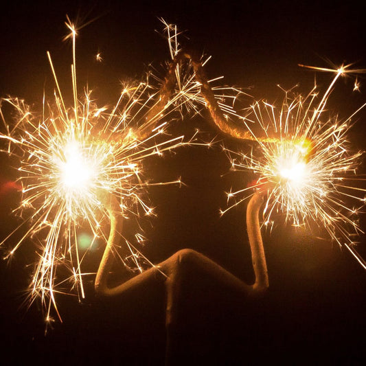 Three lit star-shaped sparklers glowing brightly with golden sparks against a dark background.
