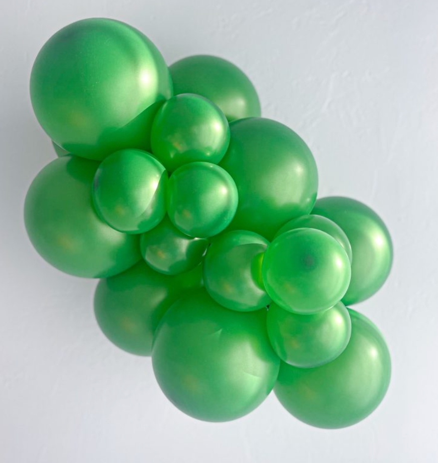 Cluster of shiny metallic green latex balloons in various sizes arranged closely together.