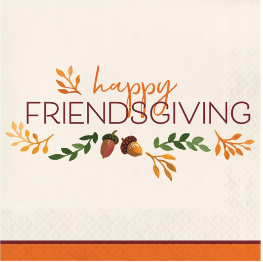 White luncheon napkin with orange border, "Happy Friendsgiving" text, and fall leaves and acorns design.