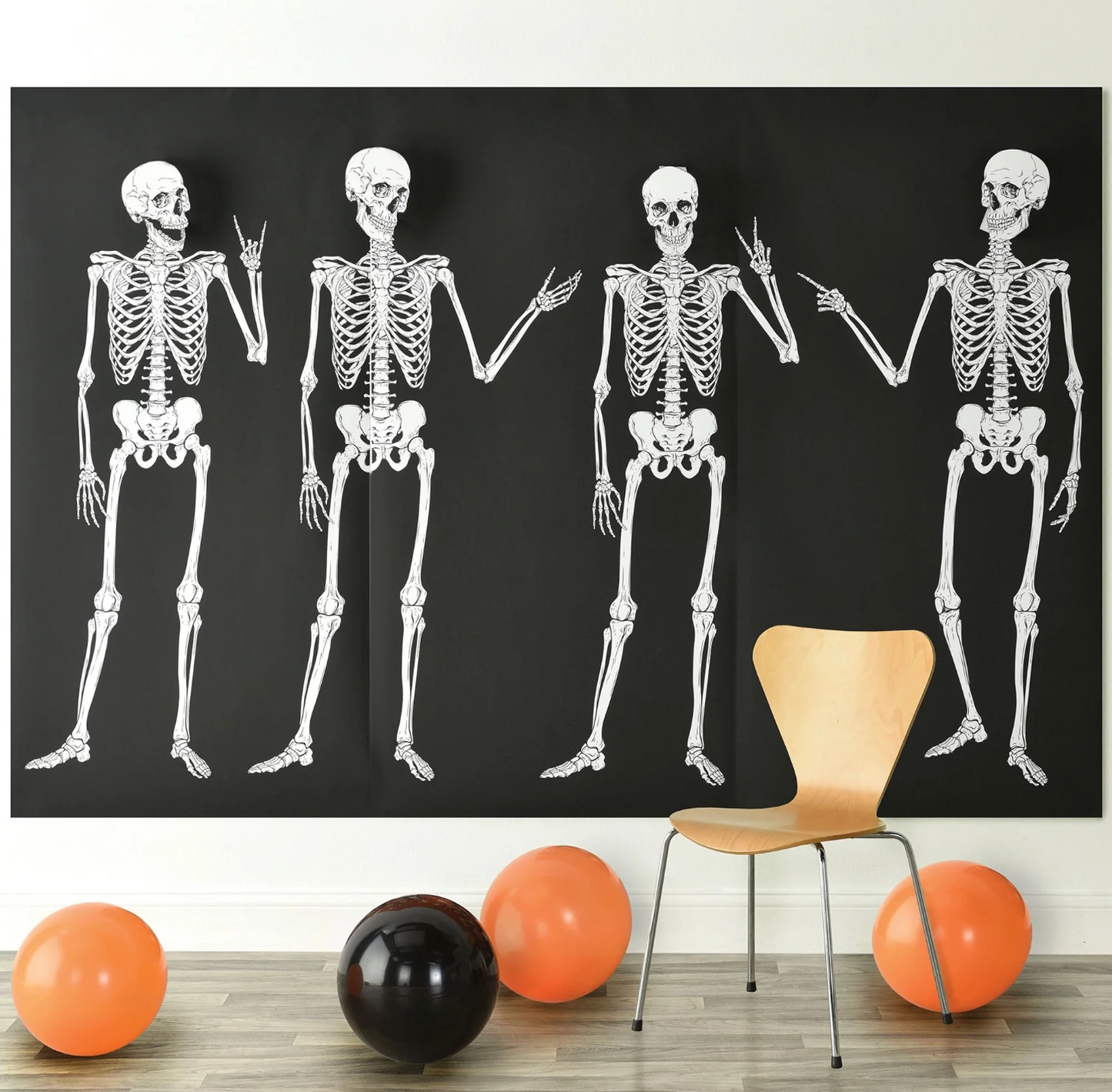 Three white skeleton backdrops on black panels with four full skeletons holding hands, surrounded by orange and black.