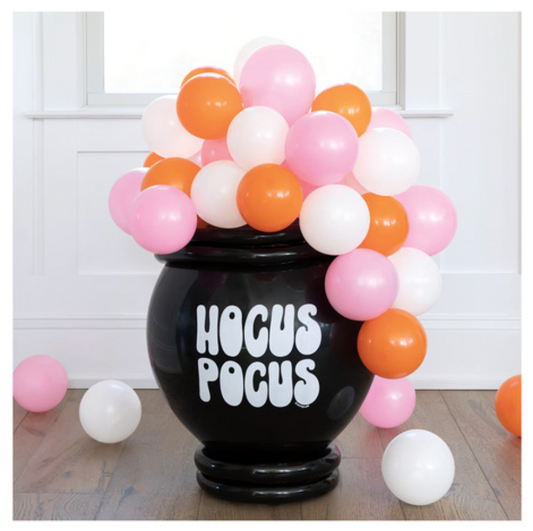 Black cauldron-shaped balloon holder with white "Hocus Pocus" text, filled with pink, orange, and white balloons.