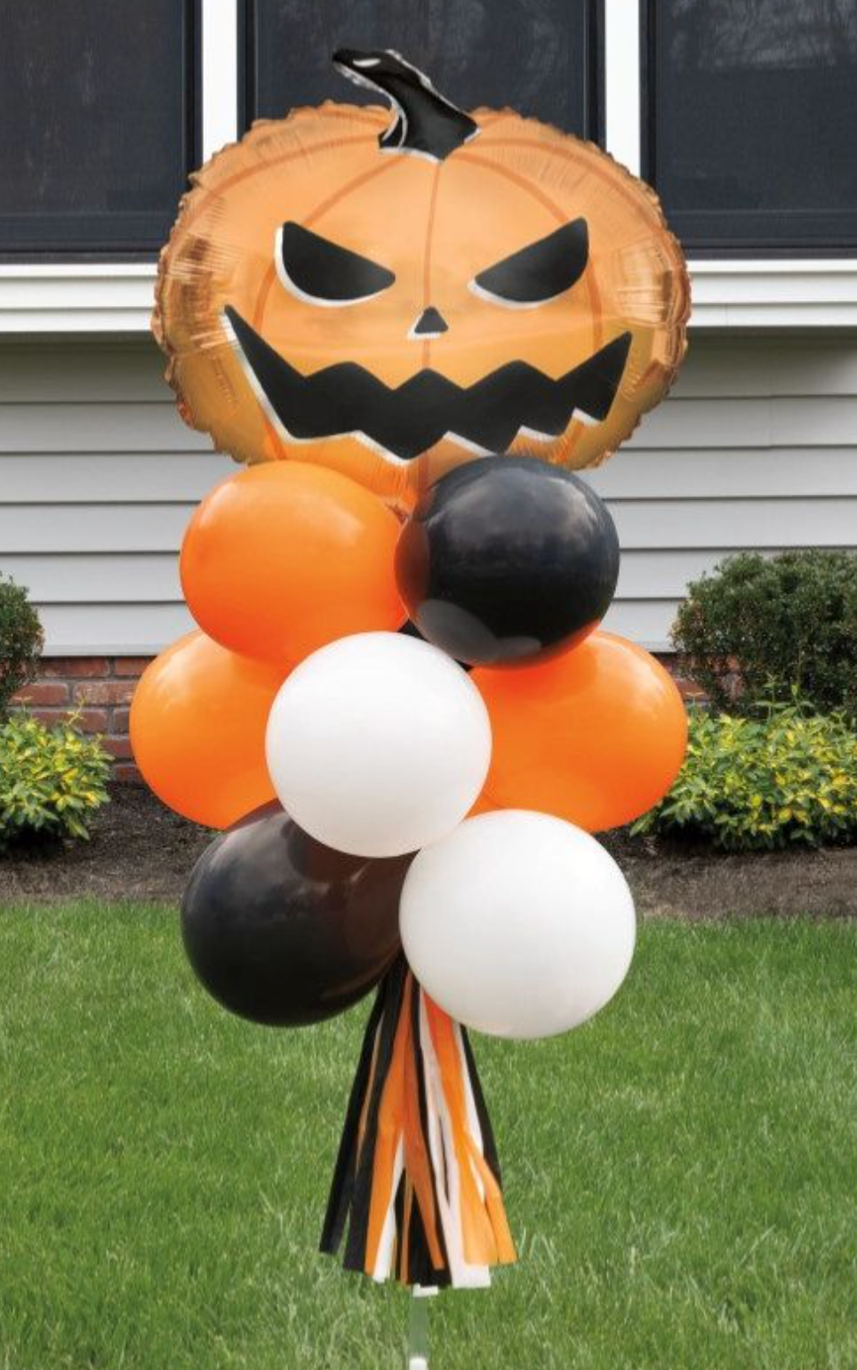 Orange foil pumpkin balloon with black jack-o'-lantern face, orange, black, and white latex balloons, and hanging fringe.
