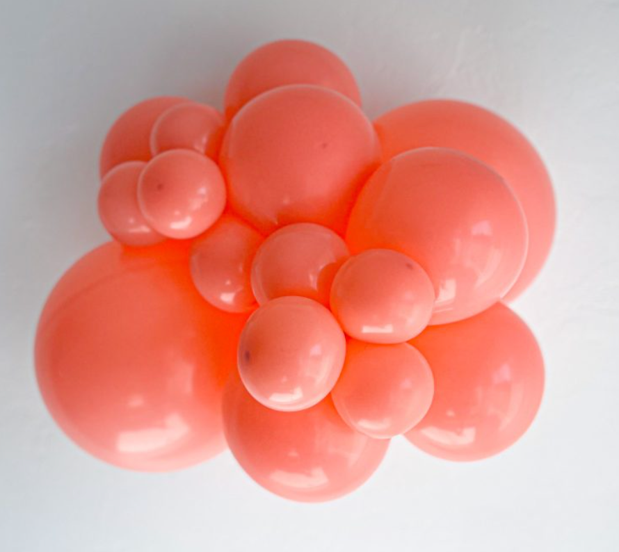 Cluster of shiny coral latex balloons in various sizes with smooth surface.