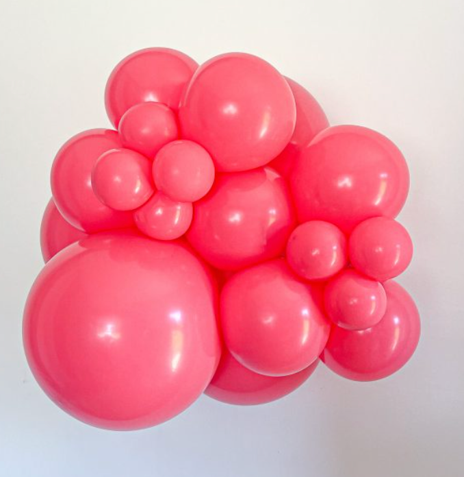 Cluster of shiny pink latex balloons in various sizes forming a decorative arrangement.