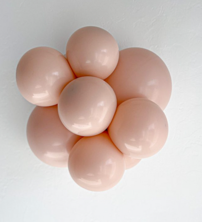 Cluster of seven round, pale pink latex balloons inflated and tightly arranged against a white background.