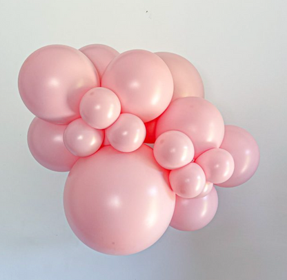 Cluster of shiny pink latex balloons in various sizes, arranged closely together.