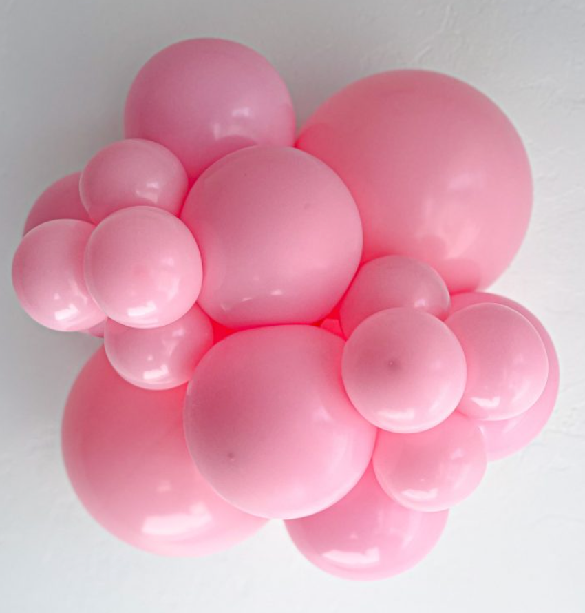 Cluster of glossy baby pink latex balloons in various sizes arranged closely together.