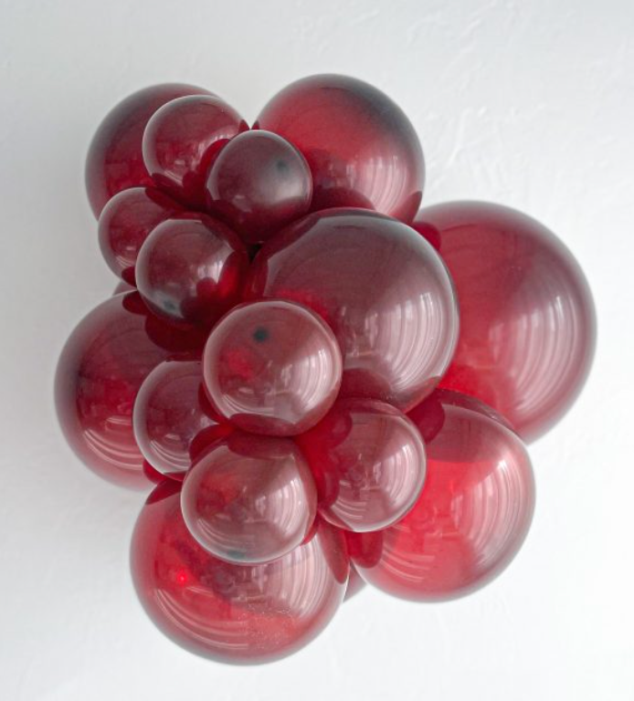 Glossy burgundy latex balloons in varied sizes clustered together on a white background.