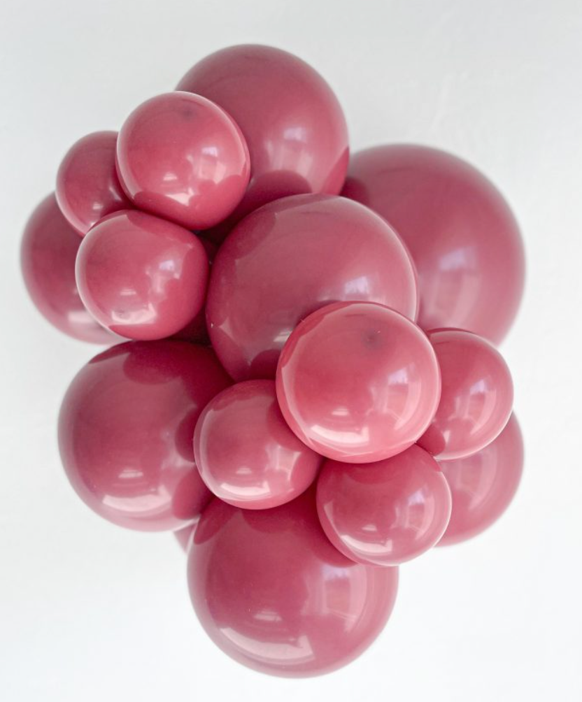 Cluster of large and small glossy red latex balloons tightly grouped together.
