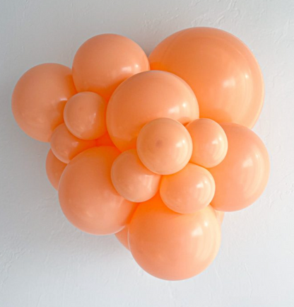 Cluster of shiny orange latex balloons in various sizes arranged closely together.