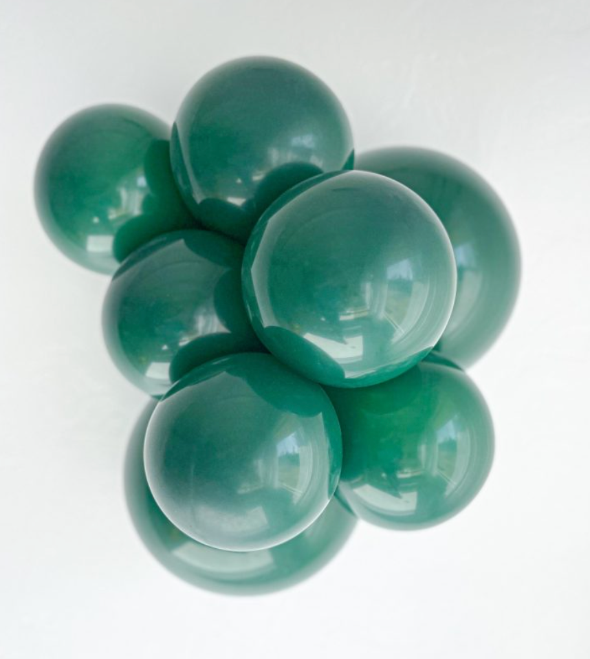 Cluster of glossy emerald green latex balloons inflated to a large 24-inch size.