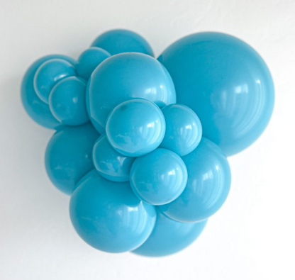 Cluster of shiny turquoise latex balloons in various sizes inflated and grouped together.