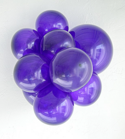 Cluster of glossy purple latex balloons inflated to varying sizes with a reflective surface.