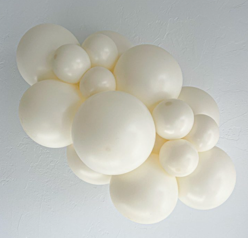 Cluster of white latex balloons in various sizes arranged in a decorative balloon garland.