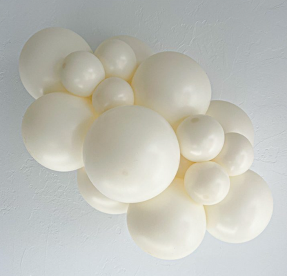 Cluster of white latex balloons in various sizes arranged in a decorative balloon garland.