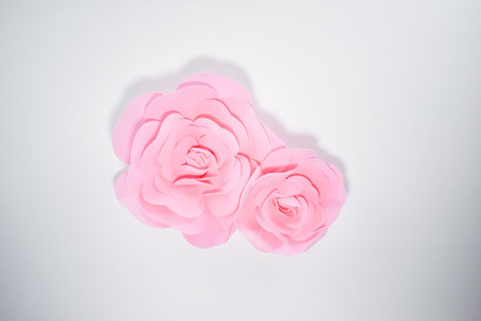 Two pink decorative paper wall flowers, one 12-inch and one 16-inch, with layered petals.