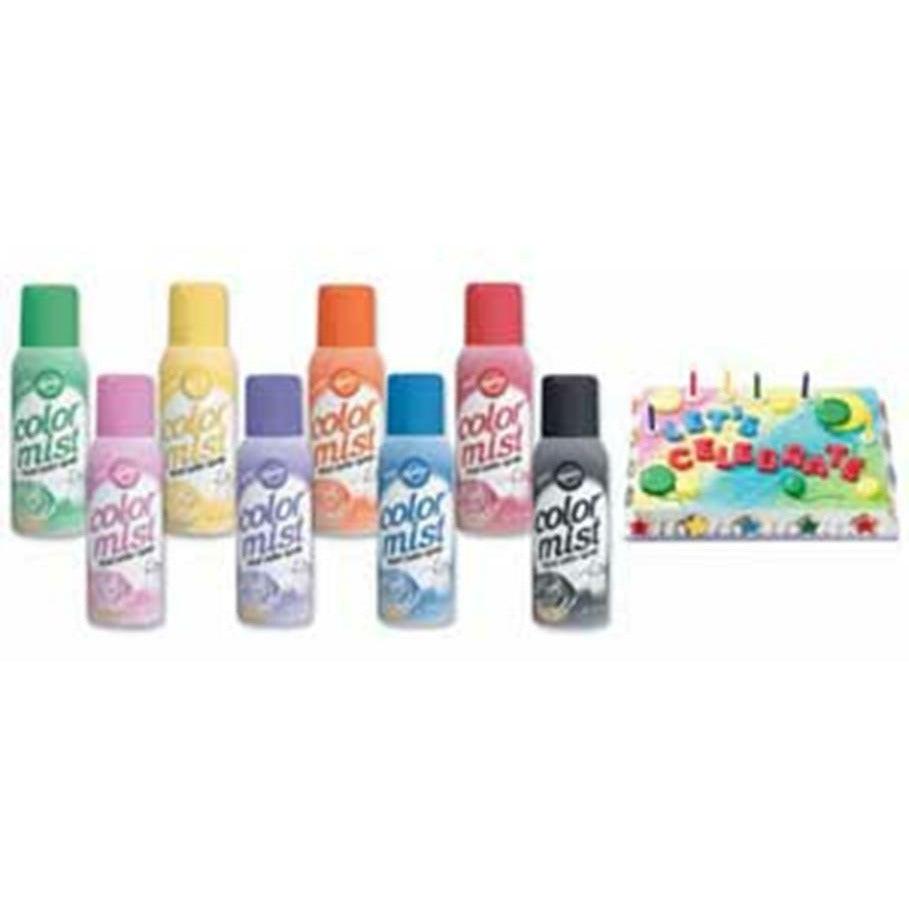 Six colorful aerosol cans of Color Mist spray paint in various shades with a decorated birthday cake in the background.